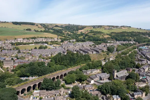 stock image Aerial drone photo of the historic Yorkshire town of Huddersfield in the UK, showing the residential housing estates with the train tracks and viaduct going through the town in the summer time