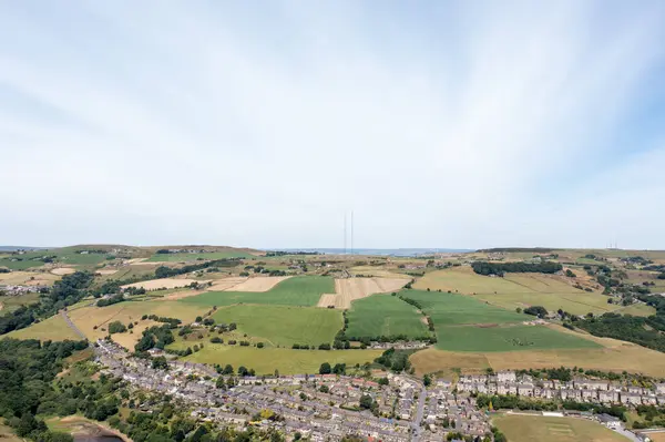 stock image Aerial photo of the historic Yorkshire town of Huddersfield in the UK, showing the residential housing estates with green fields in the background on a sunny day in the summer time