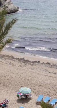 Benidorm İspanya, 14 Mart 2024: Cala del Mal Pas Sahili 'nin güneşli yaz günlerinde güneşli bir limanda güneşlenen insanlarla dolu olduğu güzel Benidorm kasabasının görüntüsü