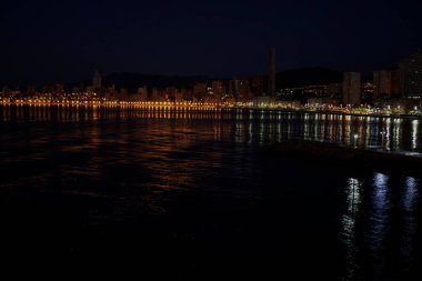 Benidorm Playa Levante plajının gece fotoğrafı, oteller, binalar, restoranlar ve Benidorm 'un sahil şeridi ve kumlu plajları İspanya' daki Alicante tatil köyü..