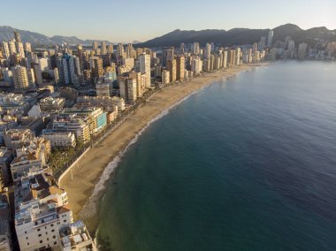 Aerial photo taken in Benidorm in Spain Alicante, showing the beautiful beach of Playa Levante, hotels, buildings, and high rise skyline cityscape with people relaxing on the beautiful beach clipart