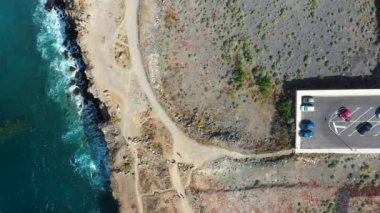Costa Adeje, Santa Cruz de Tenerife 'nin güzel hava aracı görüntüleri, Playa de Ajabo plajını, yazın okyanus kenarında park etmiş arabaların olduğu bir otoparkın yanında gösteriyor..