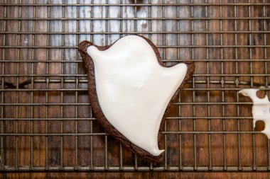 A halloween cookie in the shape of a ghost or ghoul on a baking trey with white icing clipart