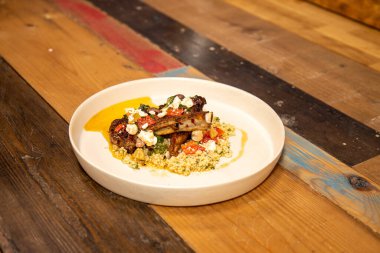 Lezzetli bir tabak ızgara kuzu pirzola ve ahşap mutfak tepesinde baharatlı kuskus.