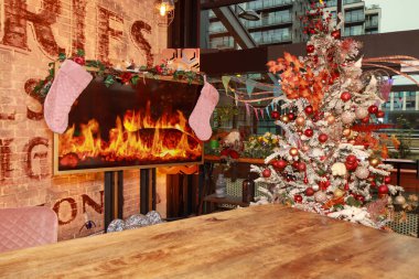 A modern Christmas living room at Christmas time showing the festive decorations and tree with a television that has been made to look like a classic warn and cosy fire place clipart