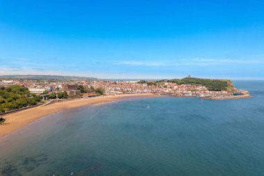Kuzey Yorkshire, İngiltere 'deki Scarborough kasabasındaki kumsalın insansız hava aracı fotoğrafı güneşli bir yaz gününde plajda eğlenen ve dinlenen insanları gösteriyor.