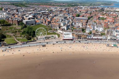 Kuzey Yorkshire, İngiltere 'deki Scarborough kasabasındaki kumsalın insansız hava aracı fotoğrafı güneşli bir yaz gününde plajda eğlenen ve dinlenen insanları gösteriyor.