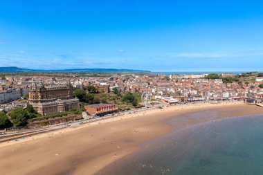 Kuzey Yorkshire, İngiltere 'deki Scarborough kasabasındaki kumsalın insansız hava aracı fotoğrafı güneşli bir yaz gününde plajda eğlenen ve dinlenen insanları gösteriyor.