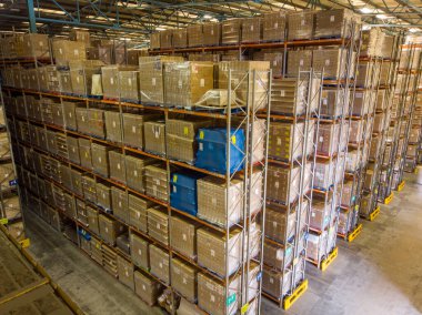 Leeds UK, 25th August 2019: Photo of the inside of a warehouse showing rows of storage boxes and containers on a storage rack showing the industrial pallet racking system and boxes clipart