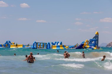 Benidorm İspanya, 29 Haziran 2024: İspanya 'daki Benidorm plajının ön tarafı, güneşli bir yaz gününde okyanusun ortasında devasa bir şişirilebilir saldırı sahası gösteriyor.