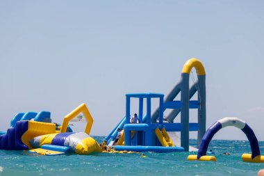 Benidorm İspanya, 29 Haziran 2024: İspanya 'daki Benidorm plajının ön tarafı, güneşli bir yaz gününde okyanusun ortasında devasa bir şişirilebilir saldırı sahası gösteriyor.
