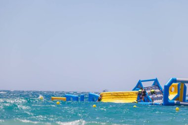 Benidorm İspanya, 29 Haziran 2024: İspanya 'daki Benidorm plajının ön tarafı, güneşli bir yaz gününde okyanusun ortasında devasa bir şişirilebilir saldırı sahası gösteriyor.