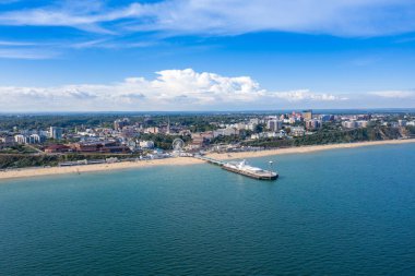 Bournemouth Sahili 'nin, Gözlem Çarkı' nın ve İskelenin insansız hava aracı fotoğrafı güneşli bir yaz gününde bir sürü insanın İngiliz Dorset kumlu plajı ve okyanusunda güneşlenmesi ve dinlenmesi.