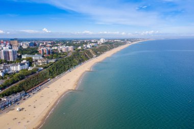 Bournemouth plajının ve şehir merkezinin güzel güneşli bir yaz gününde çekilen insansız hava aracı fotoğrafı İngiliz güneşli plajındaki kumsaldaki insanları gösteriyor.