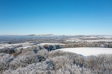 İngiltere 'nin Burnley kasabasındaki Mereclough kasabasının insansız hava aracı fotoğrafı İngiltere' de kar yağışlı bir kış gününde tarlaları ve mavi gökyüzünü gösteriyor..