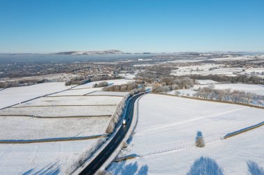 İngiltere 'nin Burnley kasabasındaki Mereclough kasabasının insansız hava aracı fotoğrafı İngiltere' de kar yağışlı bir kış gününde tarlaları ve mavi gökyüzünü gösteriyor..