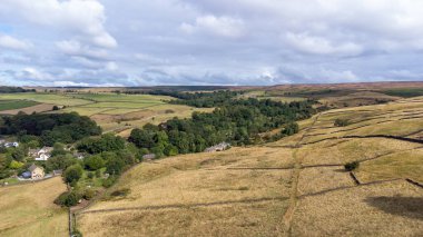 Aerial drone photo of the beautiful village of East Morton in Keighley in Yorkshire in the UK, showing old historic rows of traditional terraced houses by a road surrounded by farmers fields.
