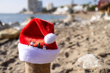 Photo on the beach of Sitio de Calahonda in Spain showing a Christmas festive Santa hat on the sand by the ocean indicating a Christmas by the sea concept clipart