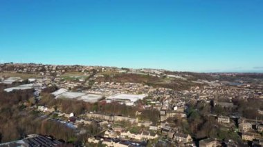 Aerial drone footage of the village of Golcar in West Yorkshire, England, Huddersfield in the UK showing the residential houses estates in the winter time with small patches of snow on the ground.
