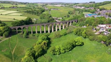 İngiltere 'nin batı Yorkshire kentindeki Bradford şehrinin metropoliten ilçesi içinde yaz mevsiminde köy ve viyadüklerin görüldüğü Thornton kasabasının insansız hava aracı görüntüleri..