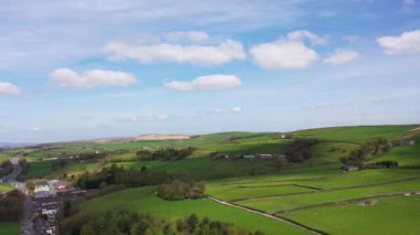 İngiltere 'nin Lancashire kentindeki Rossendale köyünün güzel yeşil tarlalarının hava aracı görüntüleri çiftçi tarlalarını mavi gökyüzü ve gökyüzünde beyaz bulutlarla gösteriyor..