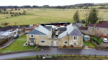Kışın soğuk bir günde İngiltere 'nin Kuzey Yorkshire kentindeki büyük çiftçi tarlalarının ve kırsal evlerin insansız hava aracı görüntüleri yukarıdan tarlalarla çevrili bir İngiliz çiftlik evini gösteriyor..