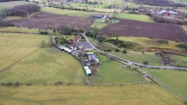 Kışın soğuk bir günde İngiltere 'nin Kuzey Yorkshire kentindeki büyük çiftçi tarlalarının ve kırsal evlerin insansız hava aracı görüntüleri yukarıdan tarlalarla çevrili bir İngiliz çiftlik evini gösteriyor..