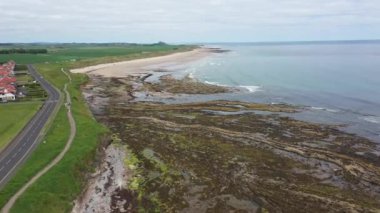 İngiltere 'nin Kuzey Northumberland kıyısındaki büyük bir köy olan Deniz Evleri köyünün sahil kasabasının havadan çekilmiş görüntüleri, yaz mevsiminde bir yol ve kumlu plajı gösteriyor..