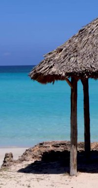 Küba 'nın Varadero plajının önündeki güzel sahilin portre görüntüleri, güneşli bir yaz gününde, okyanusun kıyısındaki ahşap bir güneş gölgesi kulübesini gösteriyor..