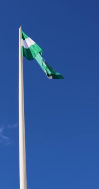 İspanya 'nın Endülüs Bölgesi bayrağının portre görüntüleri güneşli bir yaz gününde rüzgarda dalgalanan bir direkte bayrağı gösteriyor.