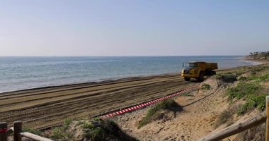 Marbella, Malaga İspanya 3 Aralık 2024 Playa de Cabopino olarak bilinen kapalı Cabopino plajının görüntüleri kumsalda kum taşıyan çöp kamyonlarını gösteriyor bu yüzden plaj kapalı.