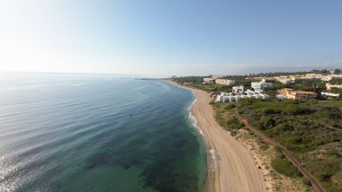 İspanya 'nın Mijas kentindeki Sitio de Calahonda kasabasındaki güzel sahil cephesinin hava aracı fotoğrafı güneşli bir aralık ayında yukarıdan kumlu plaj ve ön taraftaki daireleri gösteriyor.