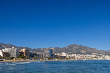 Malaga 'nın Fuengirola kıyı kasabasının önündeki güzel sahil fotoğrafında Aralık ayının güneşli bir gününde kumlu sahil, otel ve daireleri gösteren Costa Del Sol görülüyor.