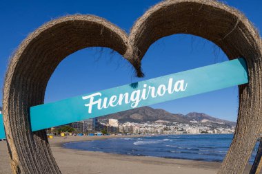 Malaga 'daki Fuengirola sahil kasabasının önündeki güzel plaj fotoğrafı. Costa Del Sol, Aralık ayında sahilde bir sokak tabelası gösteriyor.