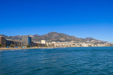 Malaga 'nın Fuengirola kıyı kasabasının önündeki güzel sahil fotoğrafında Aralık ayının güneşli bir gününde kumlu sahil, otel ve daireleri gösteren Costa Del Sol görülüyor.
