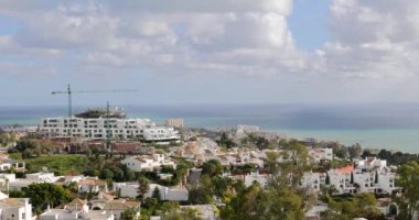 İspanya 'nın Benalmadena kenti yakınlarındaki Torremuelle kasabasının görüntüsü tepenin tepesinden bakıldığında güneşli bir günde arka planda okyanus cephesi olan kasabaya bakıyor.