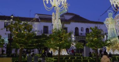 Marbella, Malaga, İspanya 8 Aralık 2024: Malaga 'nın Marbella kasabasında çekilen portre görüntüleri, İspanya' nın şenlikli Noel ışıklarını ve akşamları bir meleğin üzerindeki büyük ışıkları gösteriyor