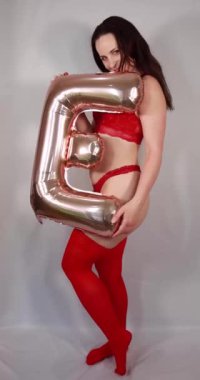 Çekici bir kadının portre görüntüleri kırmızı iç çamaşırı ve kırmızı çoraplar giymiş elinde altın bir balon olan E harfiyle aşk kelimesini heceliyor.