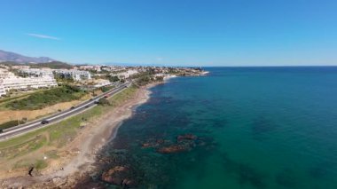 Spains Costa Del Sol 'daki Mijas kasabasında güneşli bir günde Playa del Chaparral olarak bilinen kayalık plaj cephesini gösteren hava aracı görüntüleri.