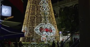 Torremolinos, Malaga İspanya, 30 Aralık 2024: İspanya 'nın Torremolinos kentindeki sokakların görüntüleri Noel şenlik ışıklarını ve sarı ışıklı büyük bir Noel ağacını gösteriyor