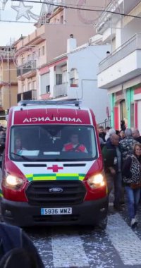 La Cala de Mijas, Malaga, İspanya 4 Ocak 2025: İspanya 'da La Cala caddesinde bulunan İspanyol ailelerinin dikey portre görüntüleri İspanyol acil durum ambulansının geçişini gösteriyor