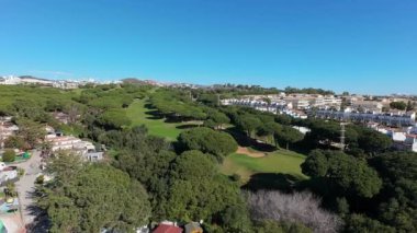 Marbella Costa del Sol İspanya 'daki Cabopino kasabasındaki hava aracı görüntüleri ağaçlarla çevrili yeşil golf sahasını ve güneşli bir günde karavan sahasını gösteriyor.