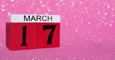 Kırmızı bir takvim bloğunun tekrar çekilip 17 Mart 'ta, yani İrlanda St Patricks' in pembe bir arka planda kutlama gününün gösterilmesi.