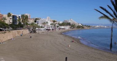 İspanya 'nın Benalmadena kasabasındaki güzel sahil cephesinin görüntüleri güneşli bir günde Playa de Santa Ana olarak bilinen plajı gösteriyor. Sadece birkaç kişi kumlu deniz kenarında güneşleniyor ve oteller var.