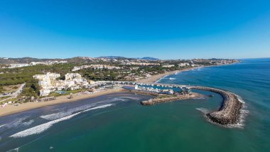 İspanya 'nın Calahonda kasabasındaki güzel sahil cephesinin hava aracı fotoğrafı Marbella İspanya' daki Cabopino limanını ve açık mavi gökyüzü günündeki kumlu plajları gösteriyor.