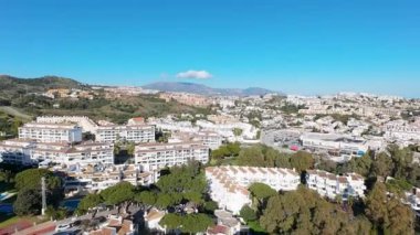 İspanya 'nın Sitio de Calahonda şehrinin hava aracı görüntüleri, güneşli bir günde arka planda dağlarla çevrili konut ve tatil evlerini gösteriyor.