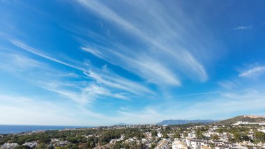 Güzel şehir Sitio de Calahonda 'nın hava aracı fotoğrafı güneşli bir mavi gökyüzünde okyanus ve dağlarla çevrili konutları ve yazlıkları gösteriyor.