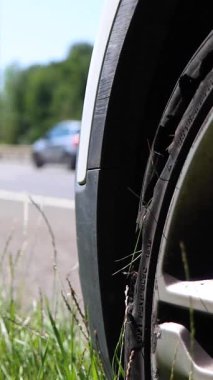 İngiltere 'de, Londra' da M25 otoyolunun lastiğinde büyük bir yarık gösteren otoyolda lastiği patlamış bir arabanın dikey portre görüntüsü.
