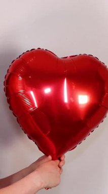 Çekici, çiçekli bir elbise giyen genç bir kadının portre görüntüleri. 14 Şubat 'ta sevgililer gününde elinde bir balon tutan bir kadın.