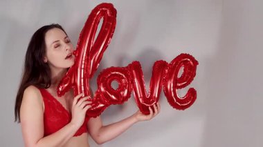 14 Şubat 'ta sevgililer gününde elinde kırmızı bir balon tutan çekici bir kadının görüntüsü. Sevgililer Günü için Aşk.